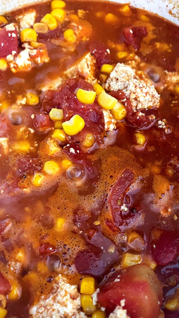 All the ingredients, corn, tomatoes, tofu are stewing together and simmering to create the tofu pasta sauce.