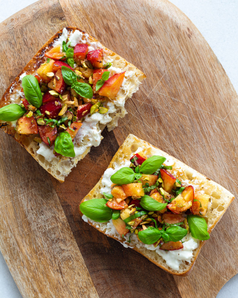 peach and burrata with pistachios and basil on olive oil toast