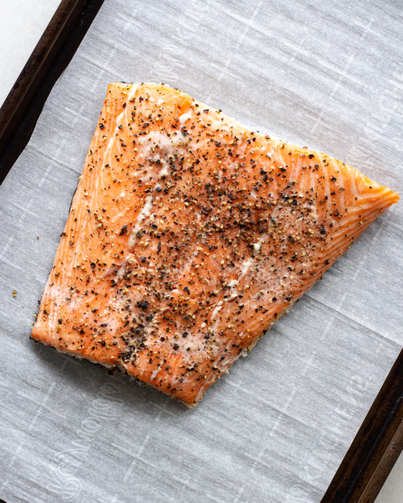 Seasoned raw salmon on baking sheet