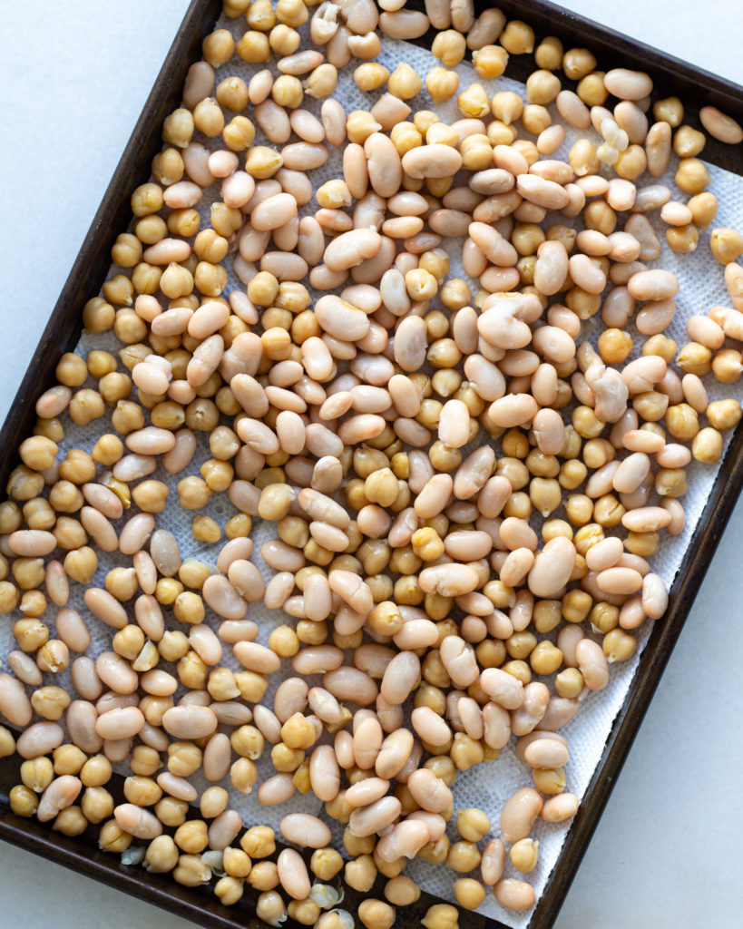 White beans and chickpeas, dried with paper towel on baking sheet