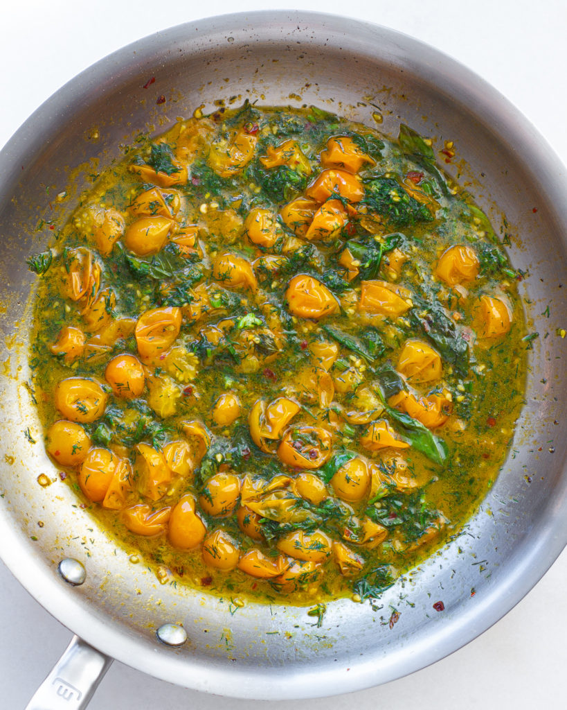 Tomatoes, dill and basil simmering in pan