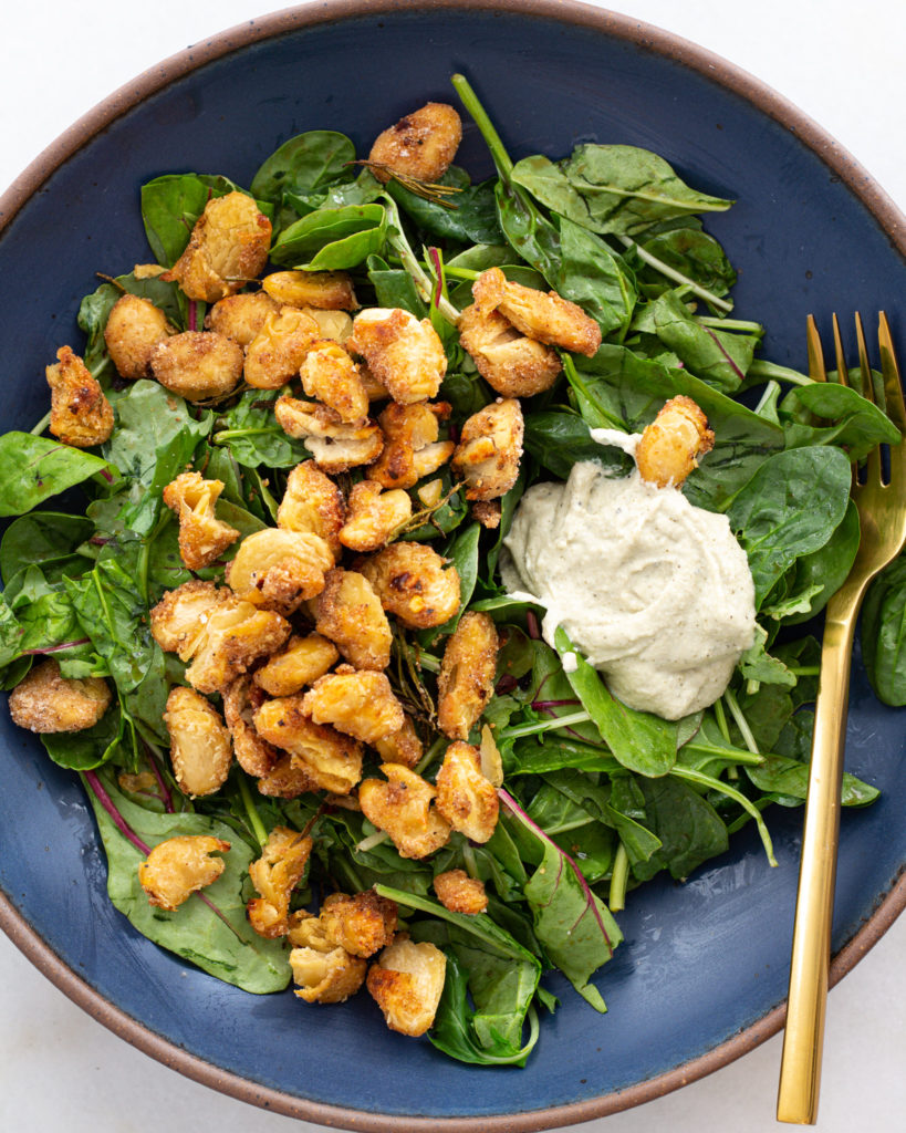 Breaded beans and cashew cream on top of a bed of spinach