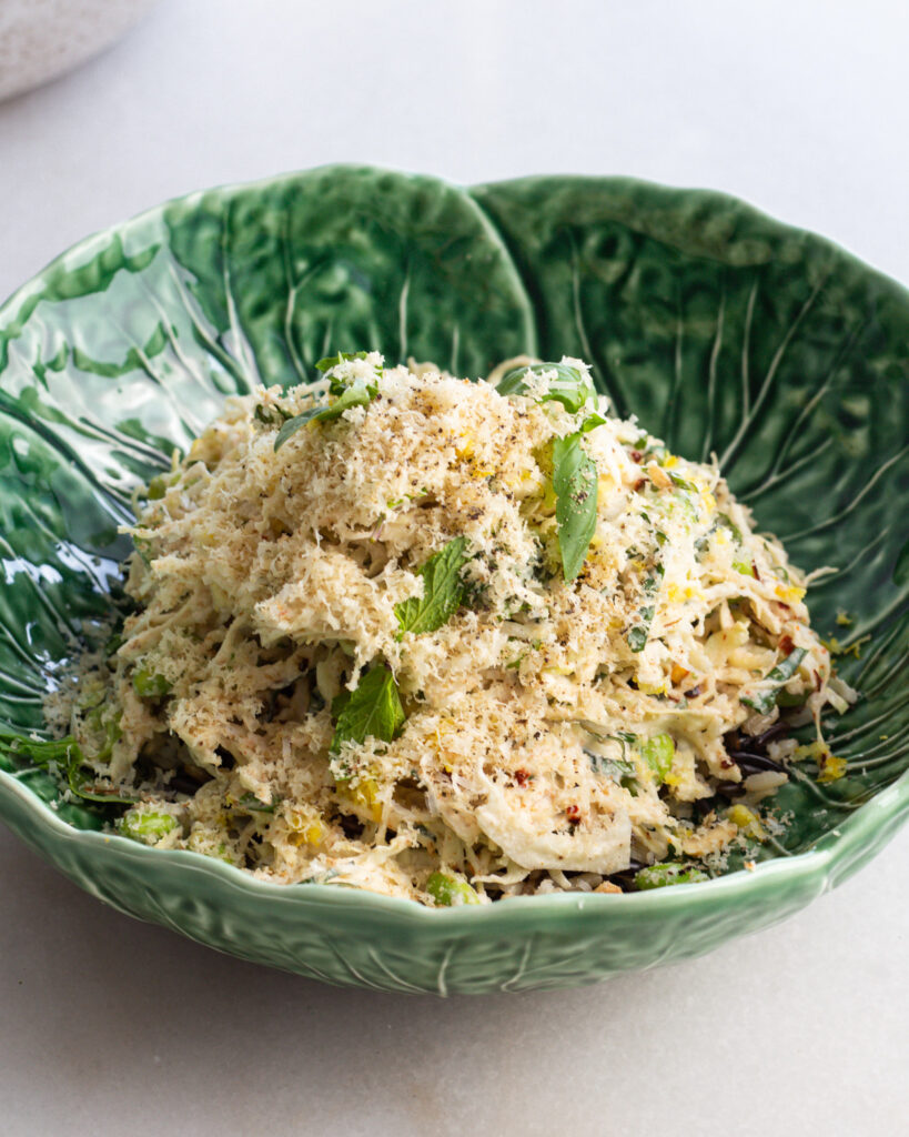Cabbage salad with charred lemon dressing topped with grated walnuts and herbs, served in a cabbage bowl