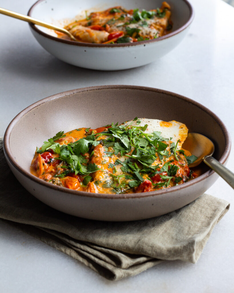 Finished tomato fish curry in bowl with spoon