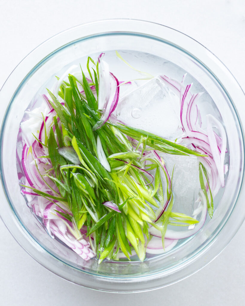 red onion and scallions soaking in ice water