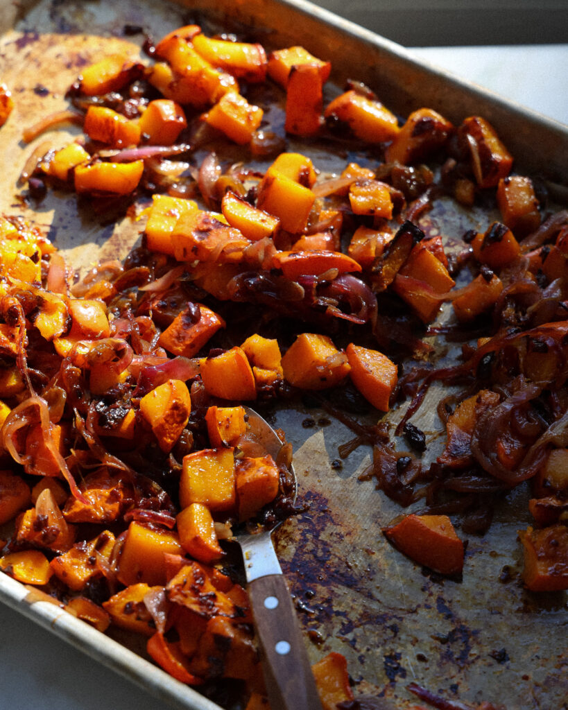 kabocha squash on a sheet pan after being tossed with the golden raisin gastrique