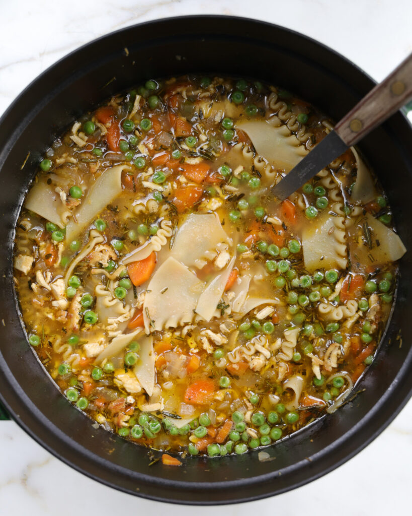 All the lasagna noodles being swirled in a pot of vegetarian chicken noodle soup