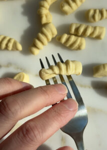 shaping homemade gripper shaped pasta with a fork.