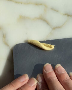 shaping homemade gemelli with a bench scraper.