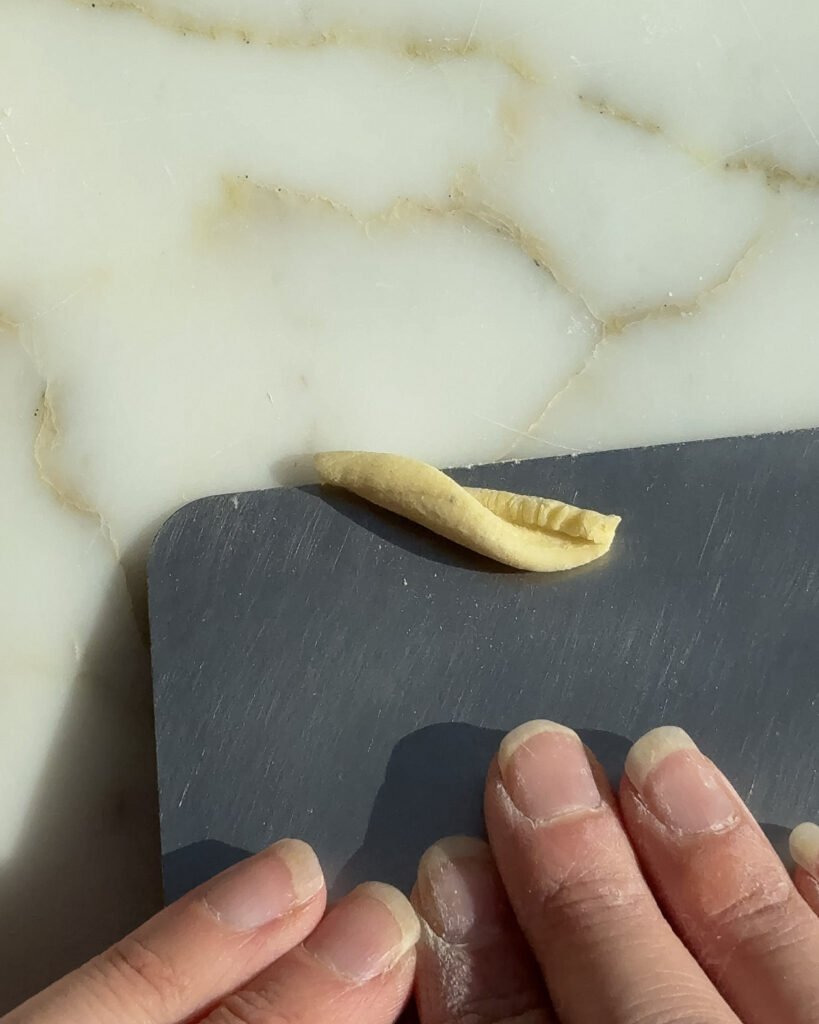 shaping homemade gemelli with a bench scraper.