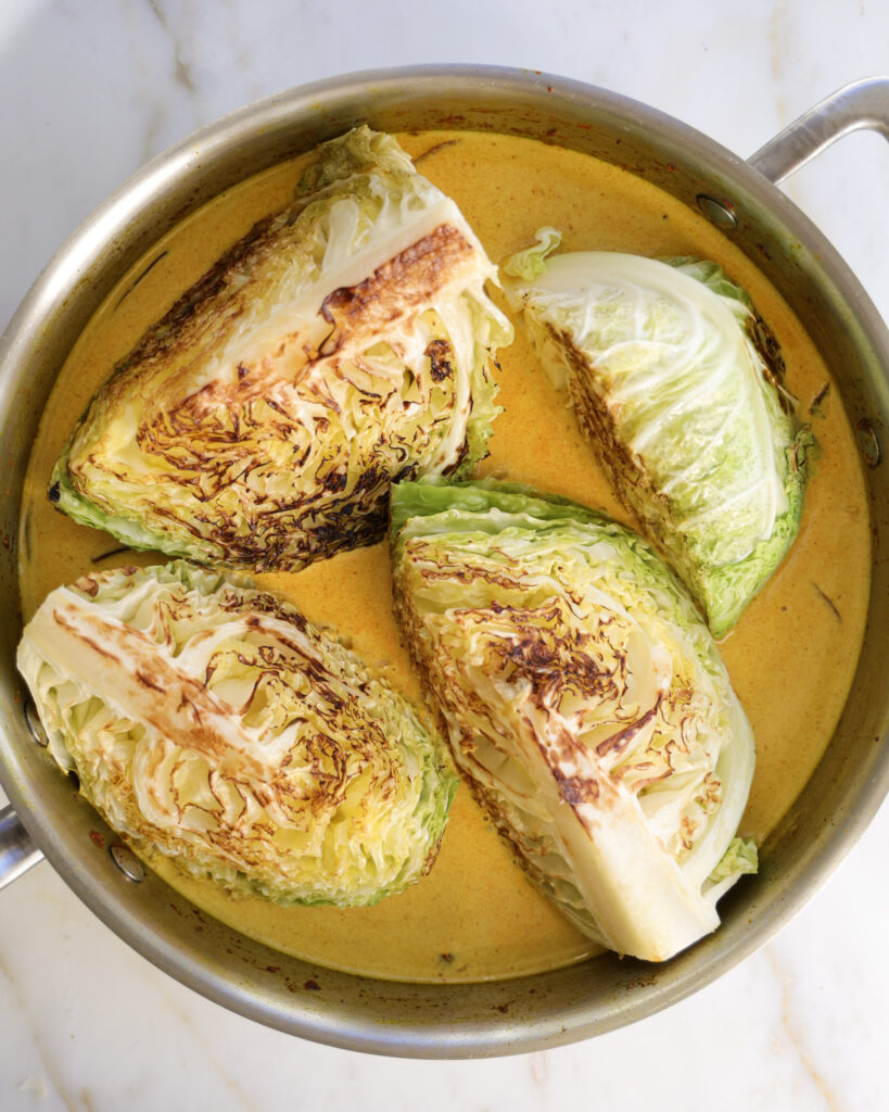 Seared cabbage wedges in braising liquid.
