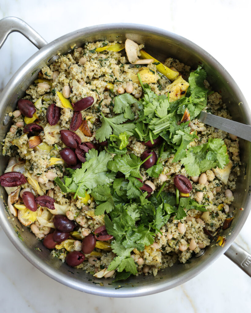 Olives and cilantro being added to lemon quinoa.
