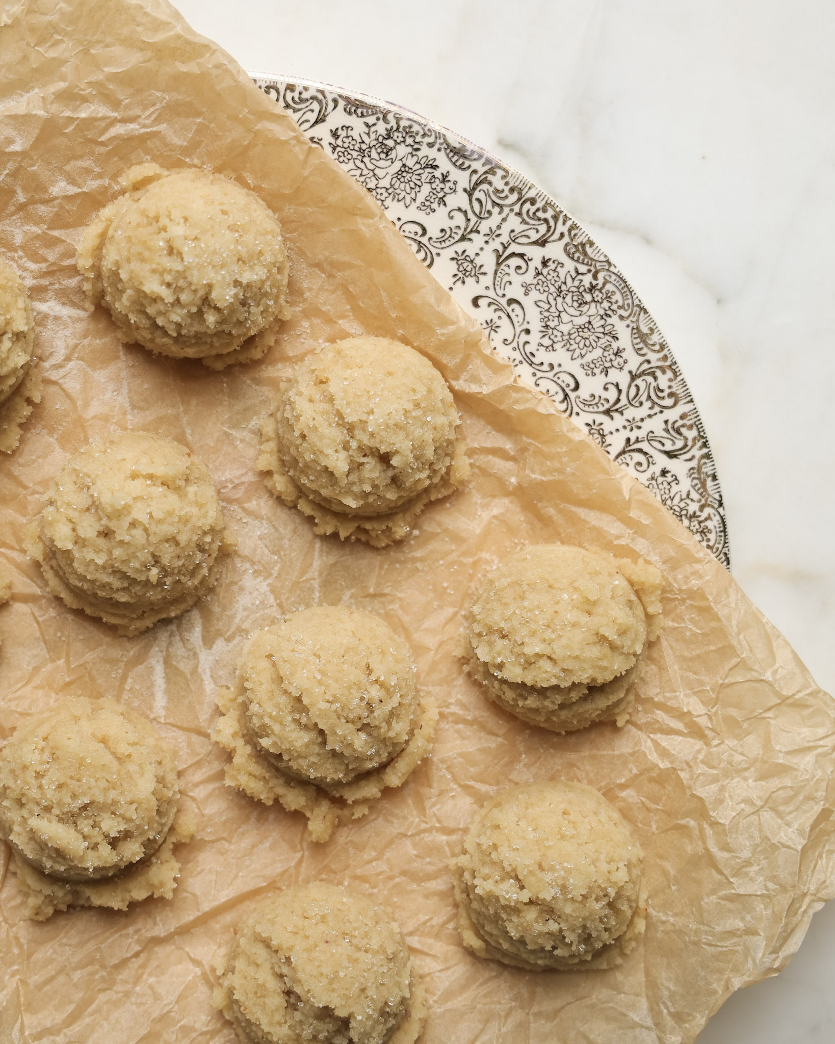 Sugar cookie dough balls on parchment paper.