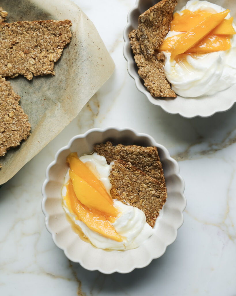 Granola bark in a bowl with yogurt and mango slices.