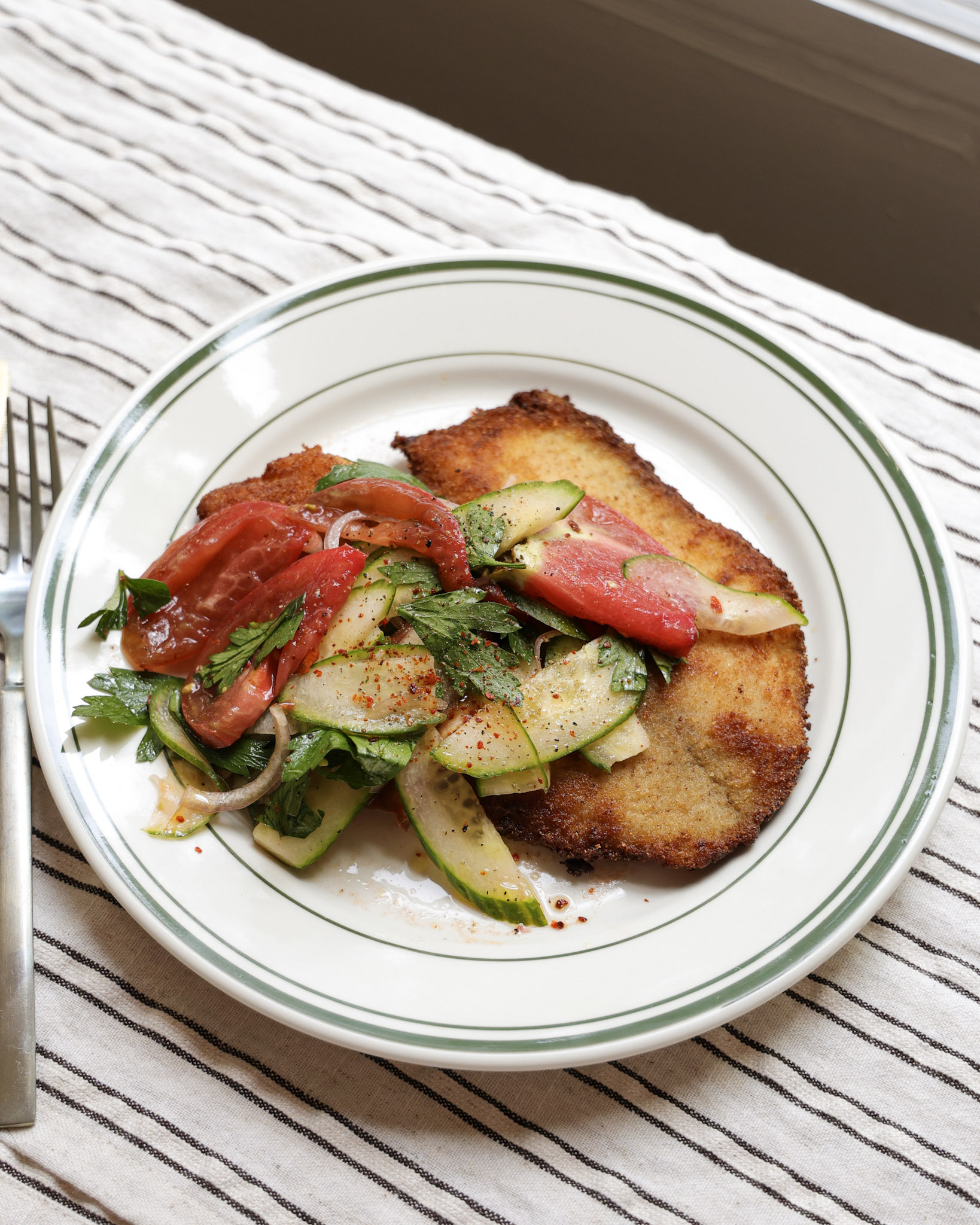 Tomato salad spooned over fried tilapia on plate.