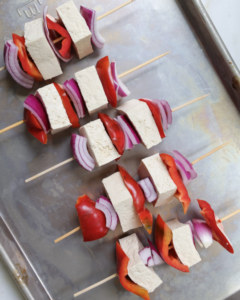 Tofu skewers uncooked on a baking sheet.