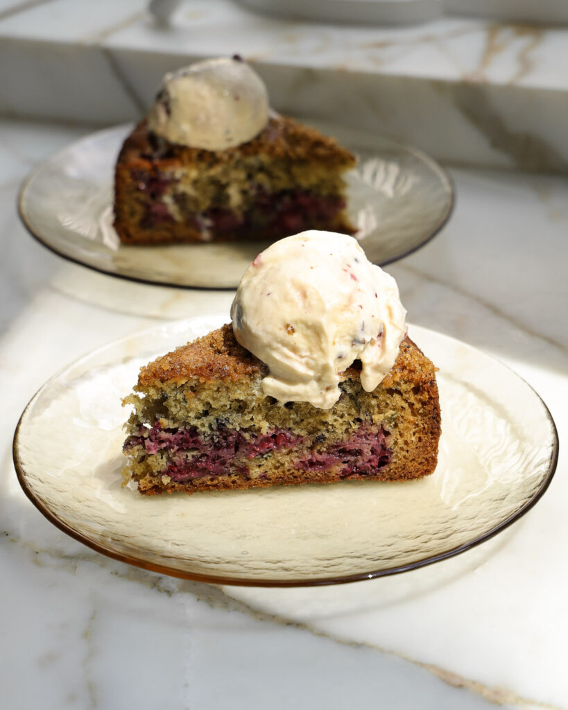 A slice of blackberry cake topped with whipped cream.