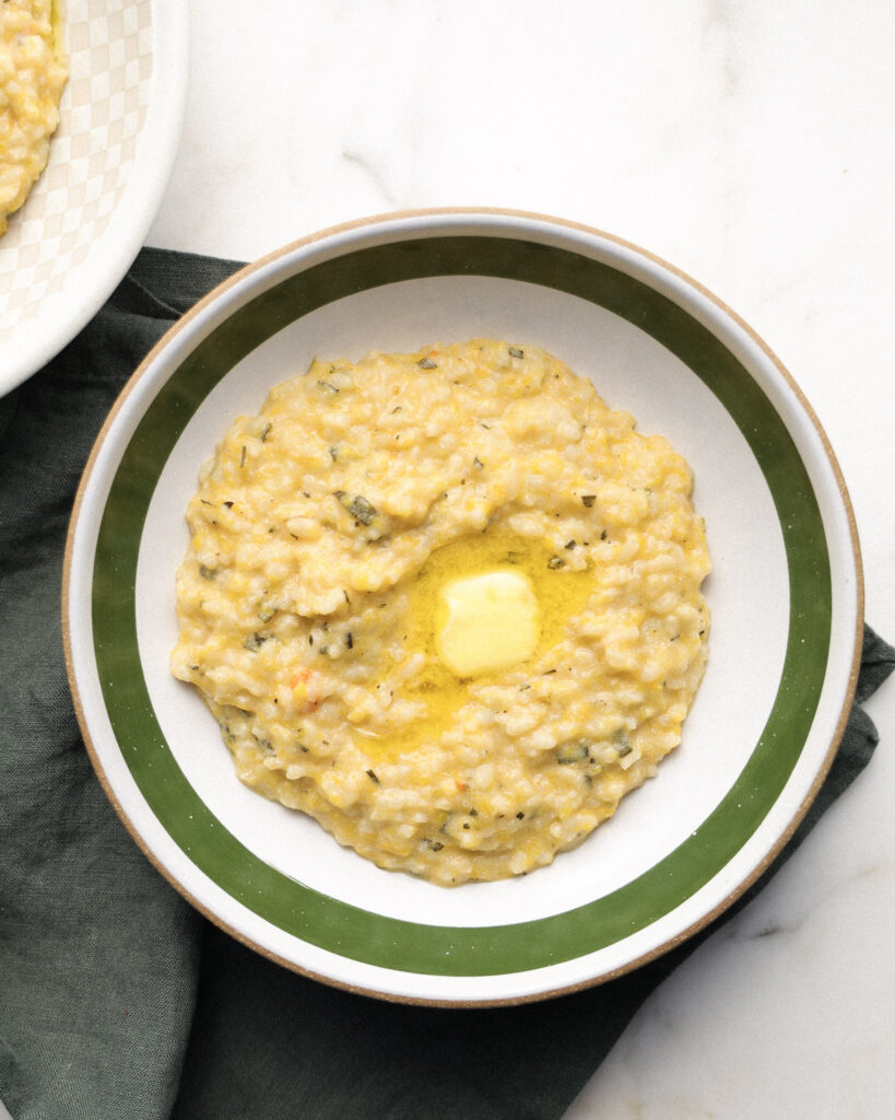 Squash risotto in a bowl topped with butter.