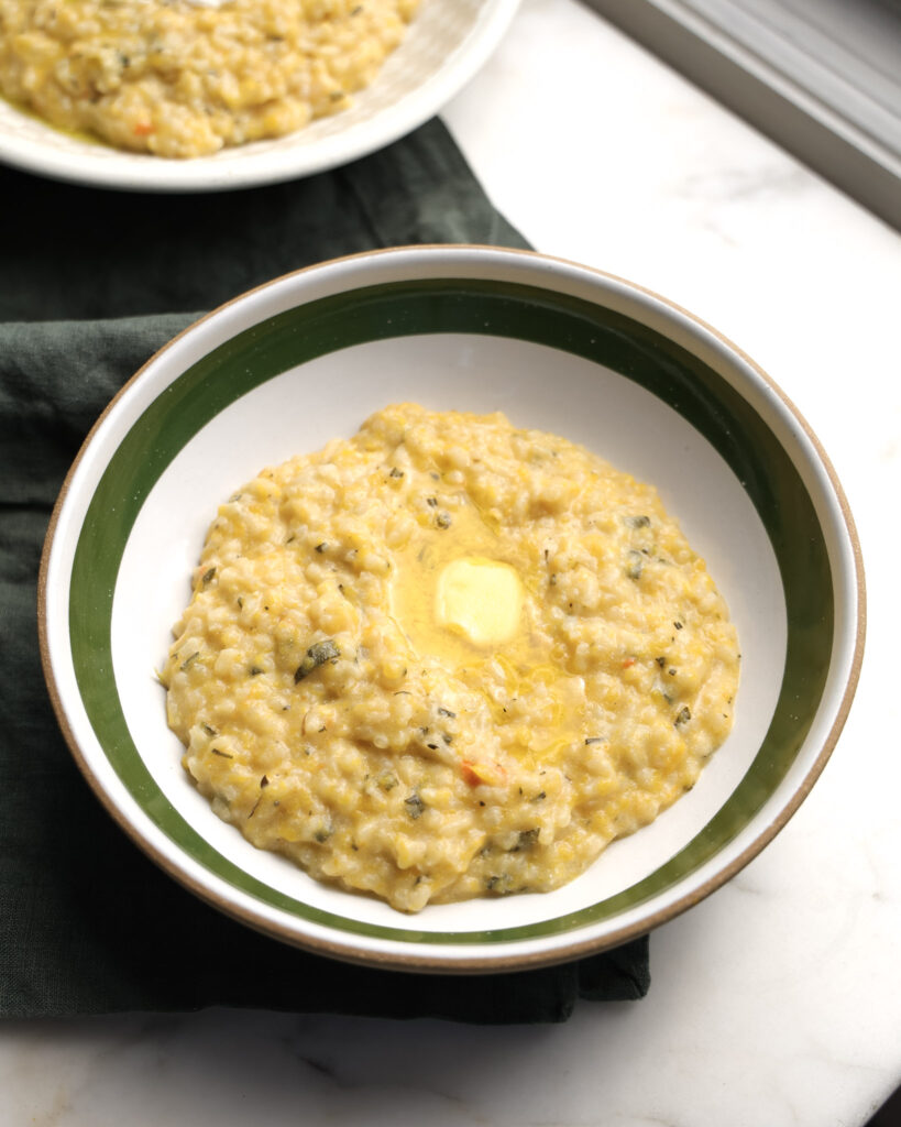 Squash-zotto in a bowl topped with butter.