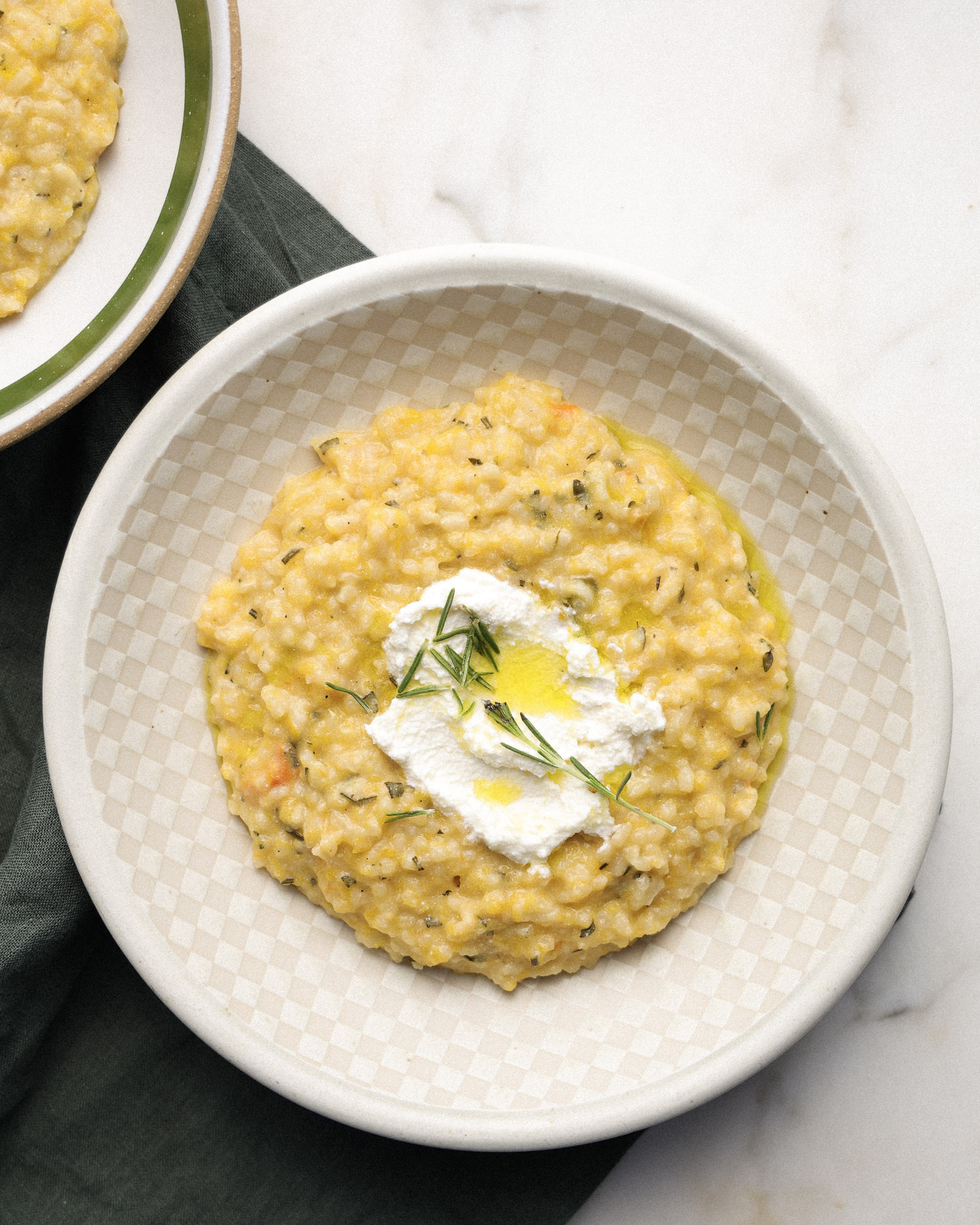 Squash risotto in a bowl topped with herb and risotto.